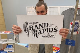 me holding up a poster of some hand lettered grand rapids type